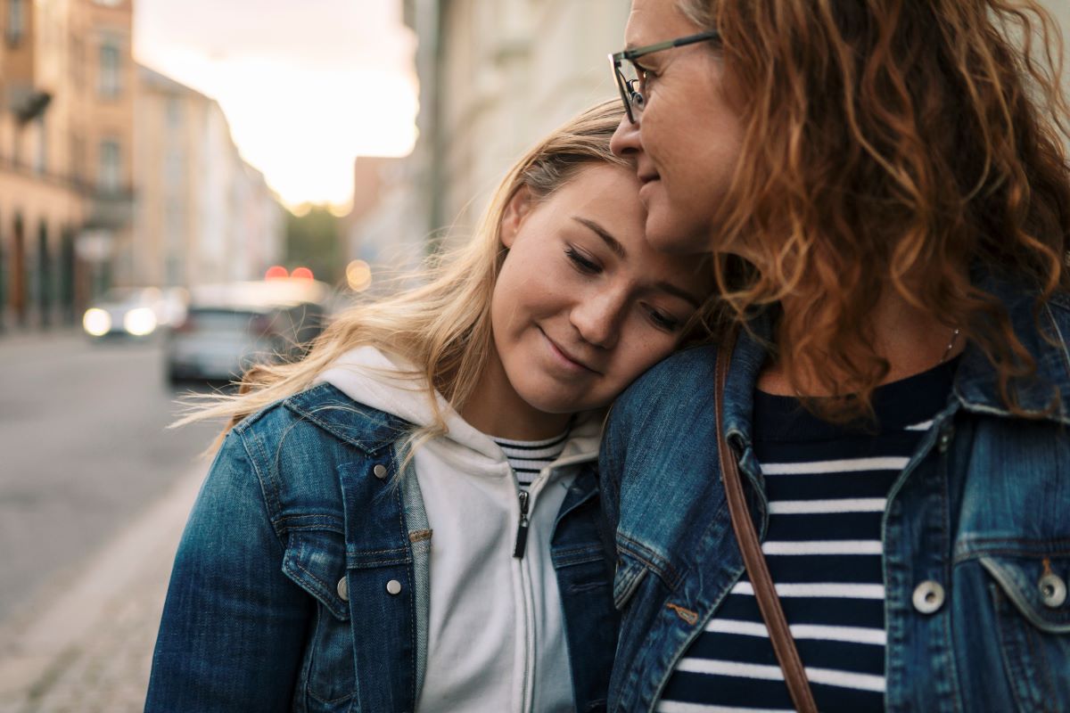mom hugging daughter on a city street