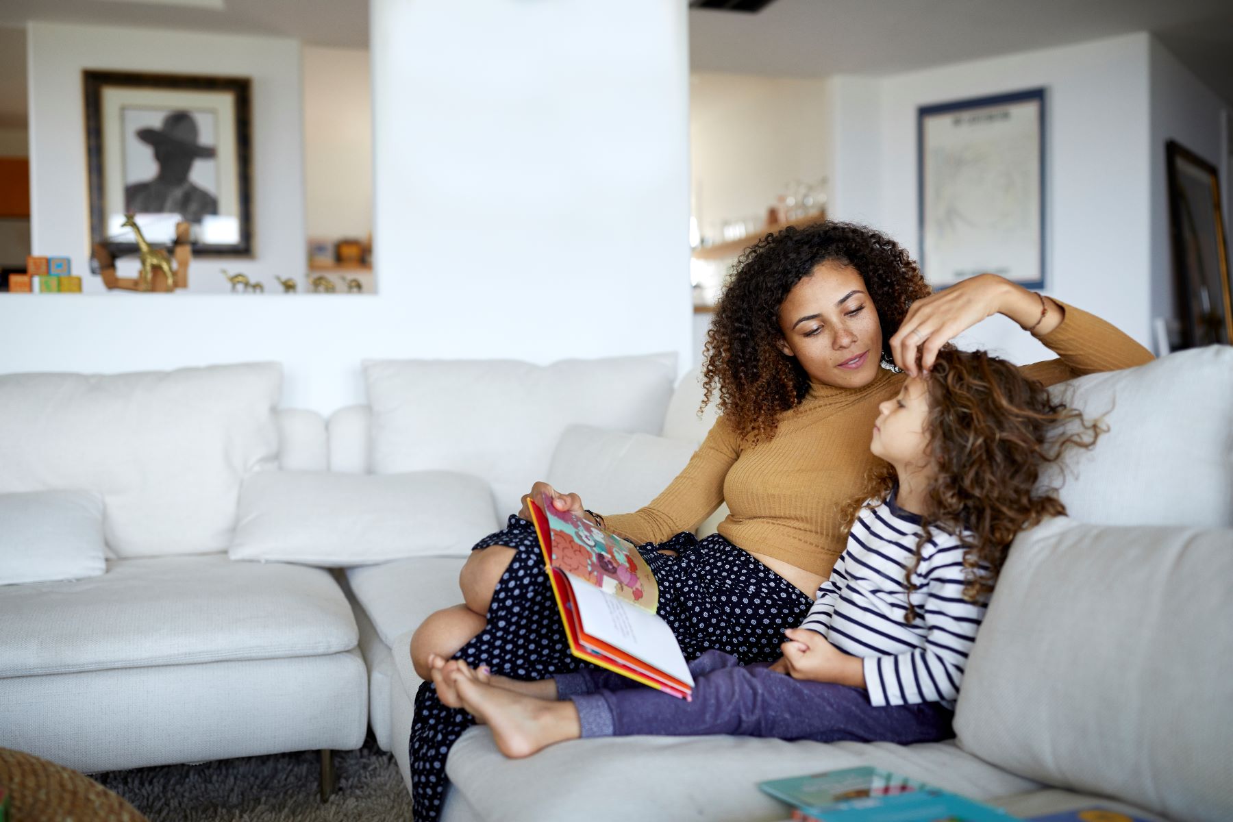 girl sits on the couch with mom next to her brushing her hair back from her face