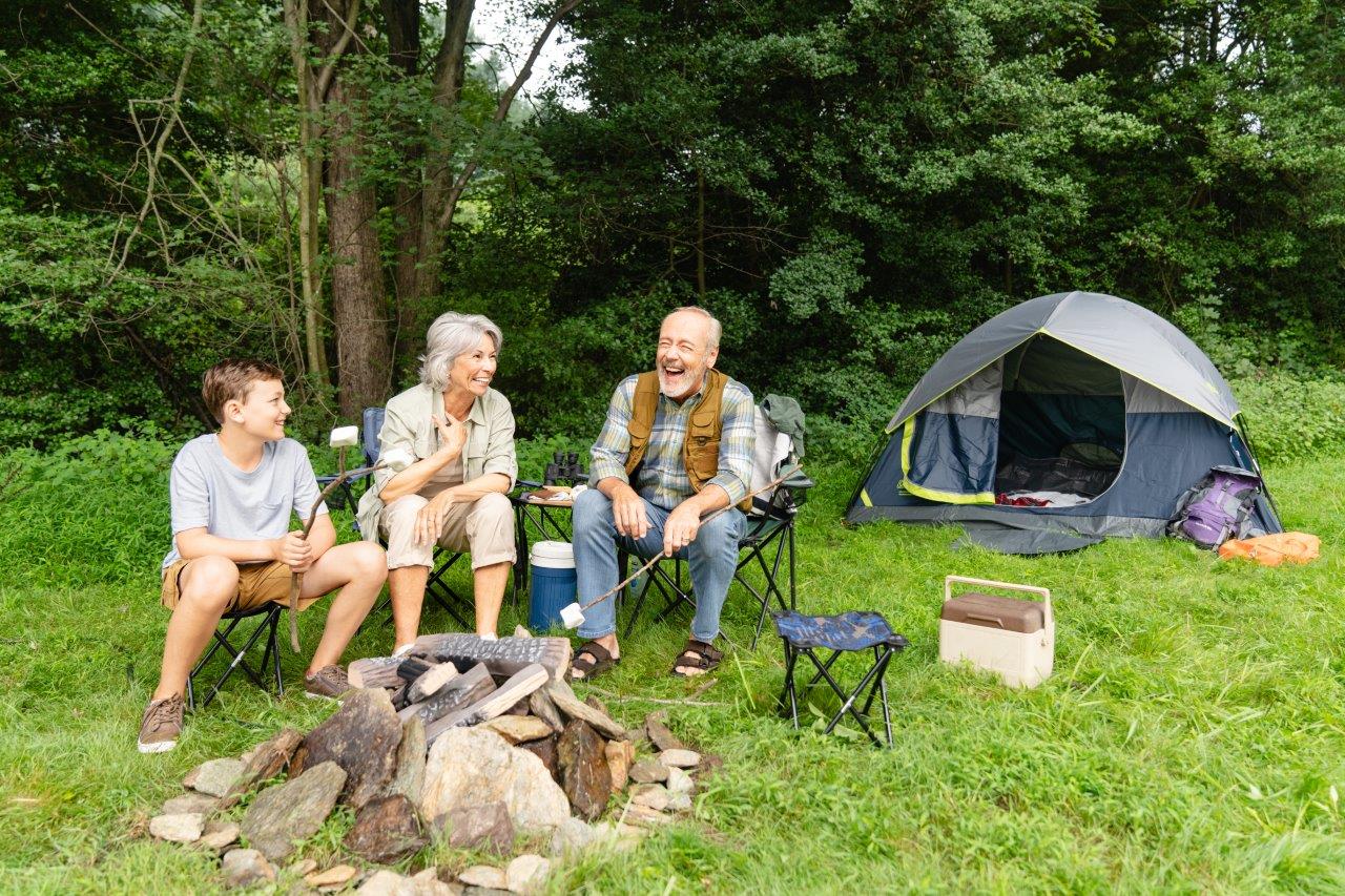 Older couple by the fire camping with their grandson