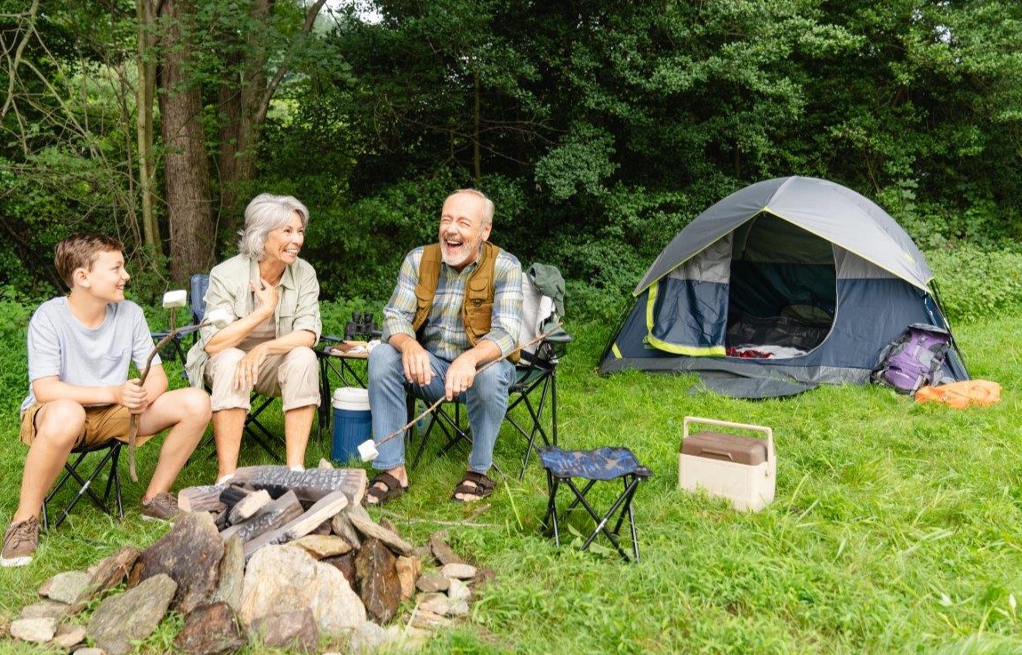 Older couple by the fire camping with their grandson