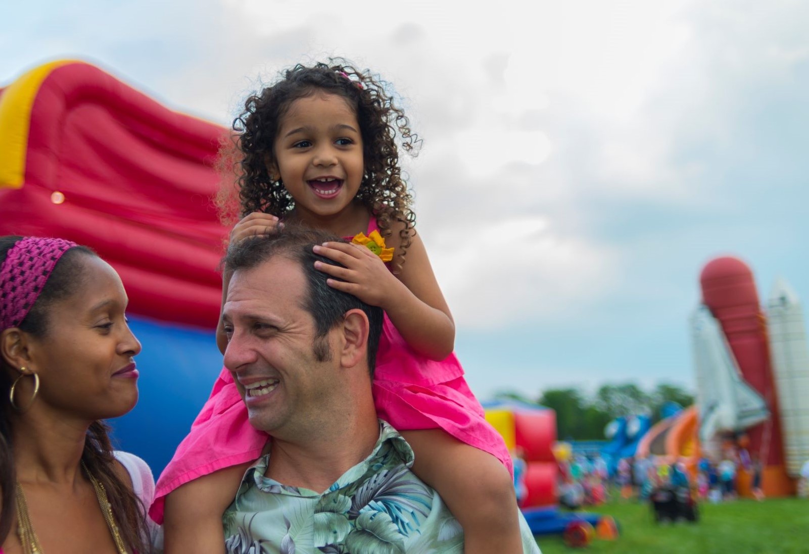 mom and dad with young daughter on his shoulders enjoy a day at the fair